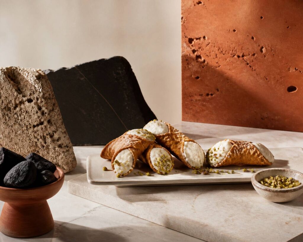 Cannoli siciliens garnis de ricotta et de pistaches sur un plat