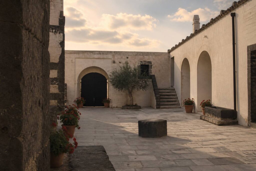 Cour pavée d'une ferme en pierre avec des géraniums
