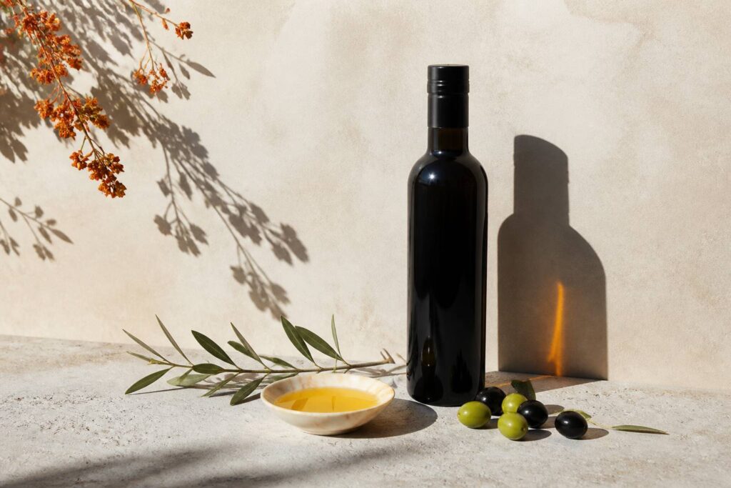 Bottiglia scura di olio extravergine siciliano con olive fresche e olio dorato su pietra chiara